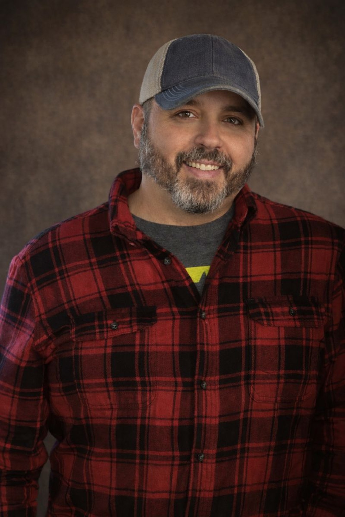 Author Shannon L. Salley smiling in a red plaid shirt and cap